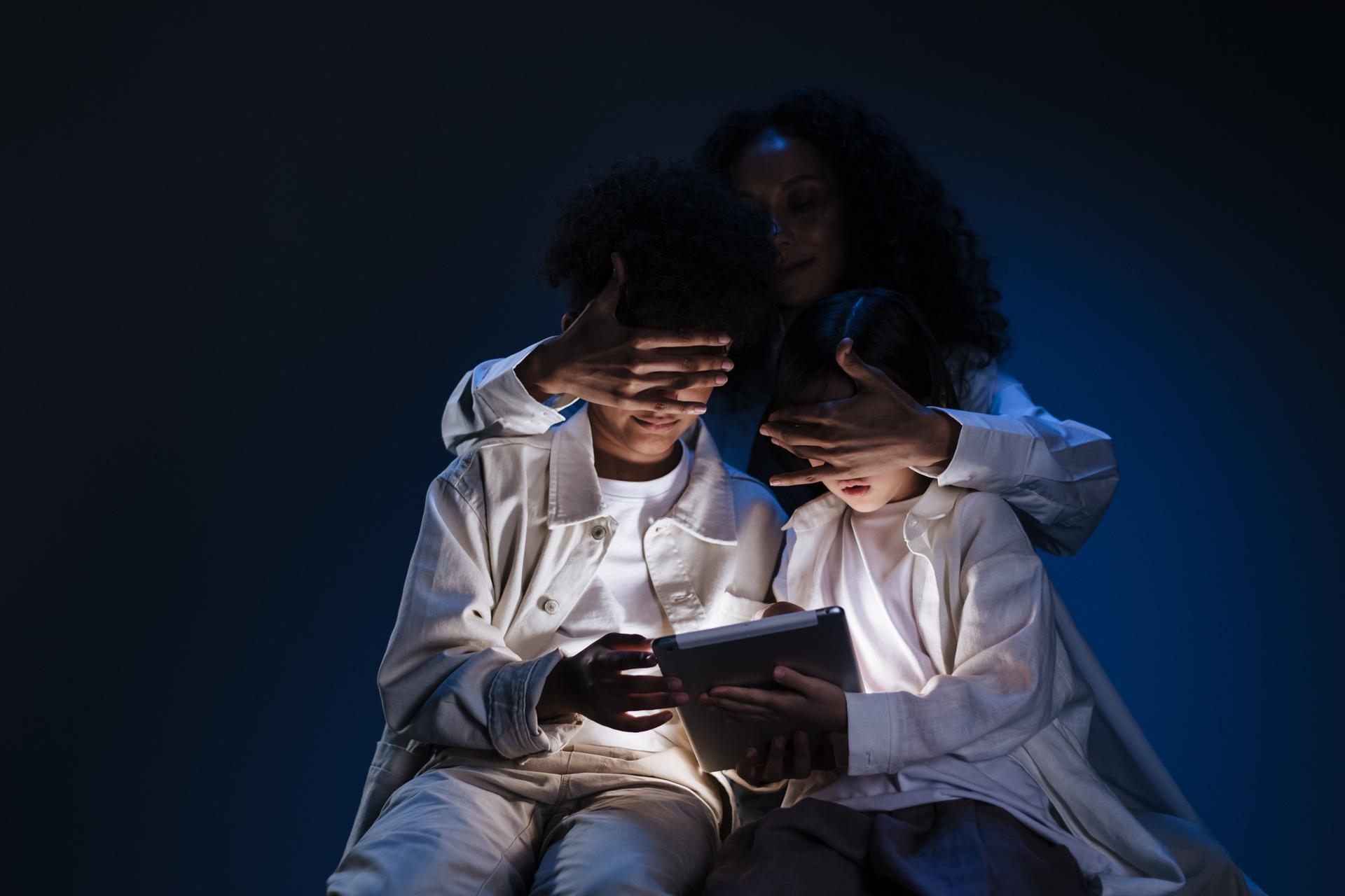 An adult obscuring children's faces while they engage with a tablet, highlighting user privacy concerns in AI agents.
