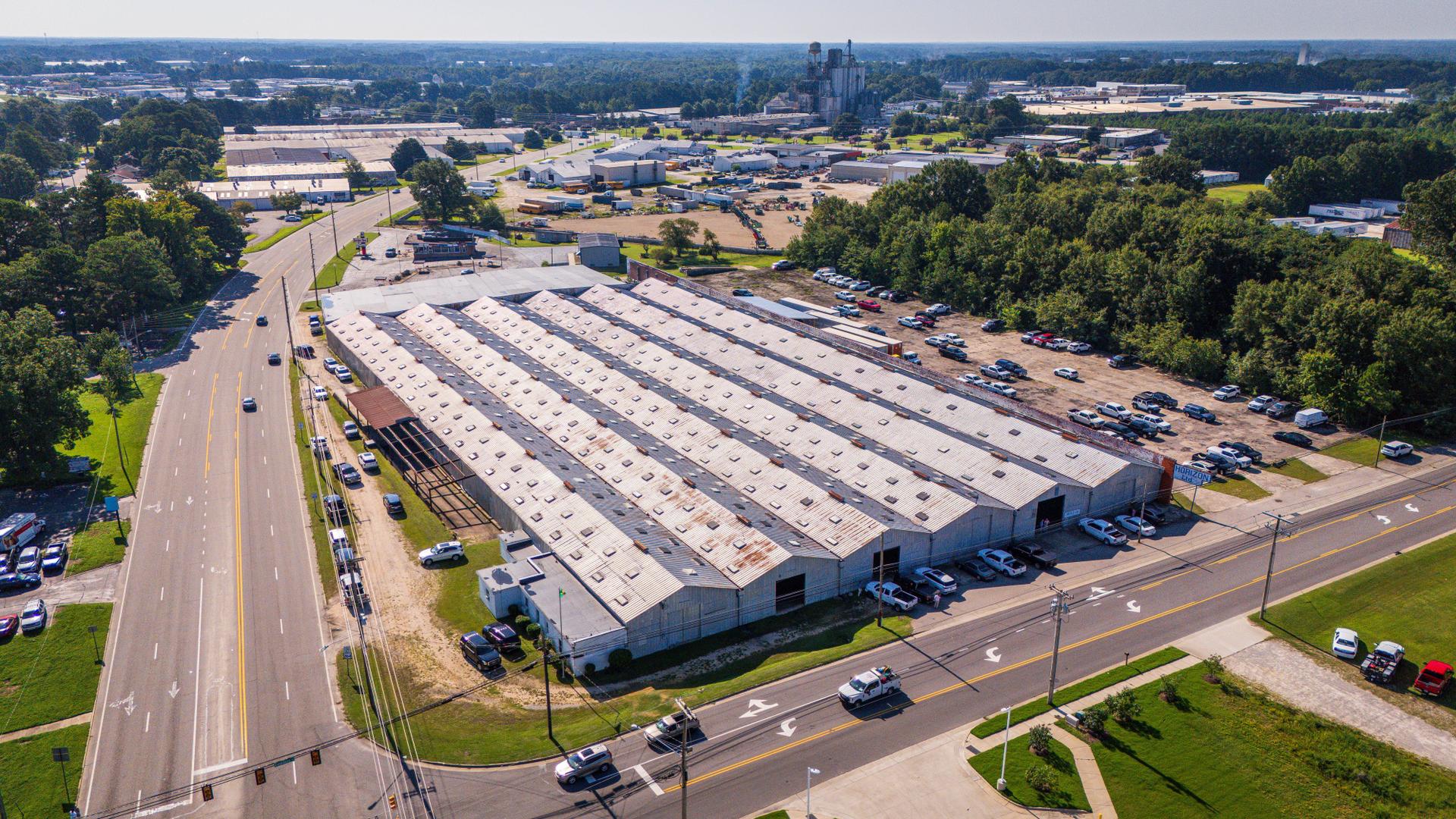 Aerial view of a warehouse supporting data center infrastructure, surrounded by vehicles and greenery.