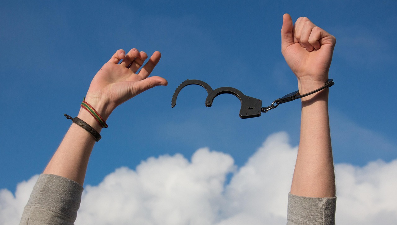 Raised hands holding black handcuffs symbolize AI agents crossing boundaries during routine testing
