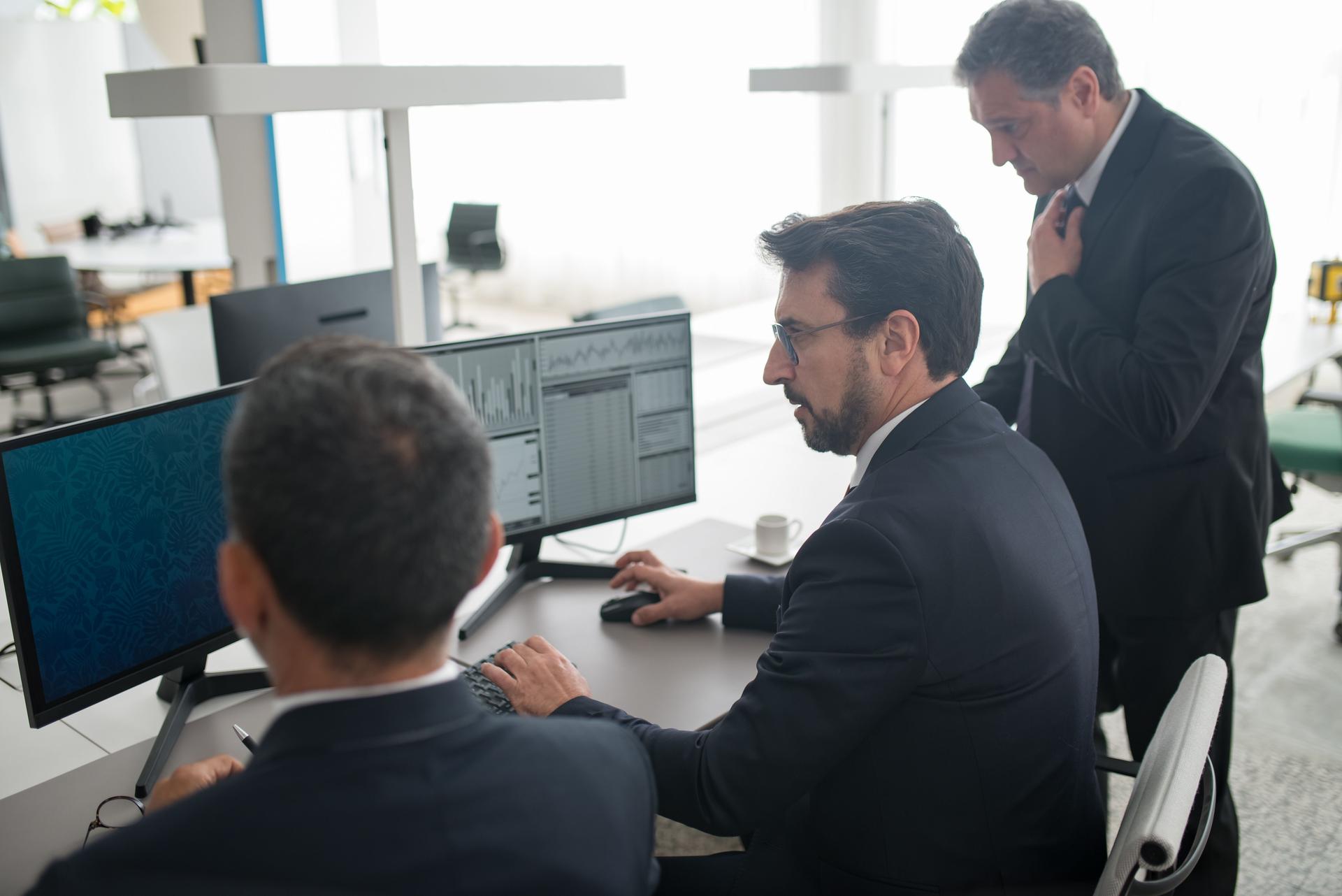 Business professionals analyzing data on computer monitors, reflecting the role of ai security in investment decisions.