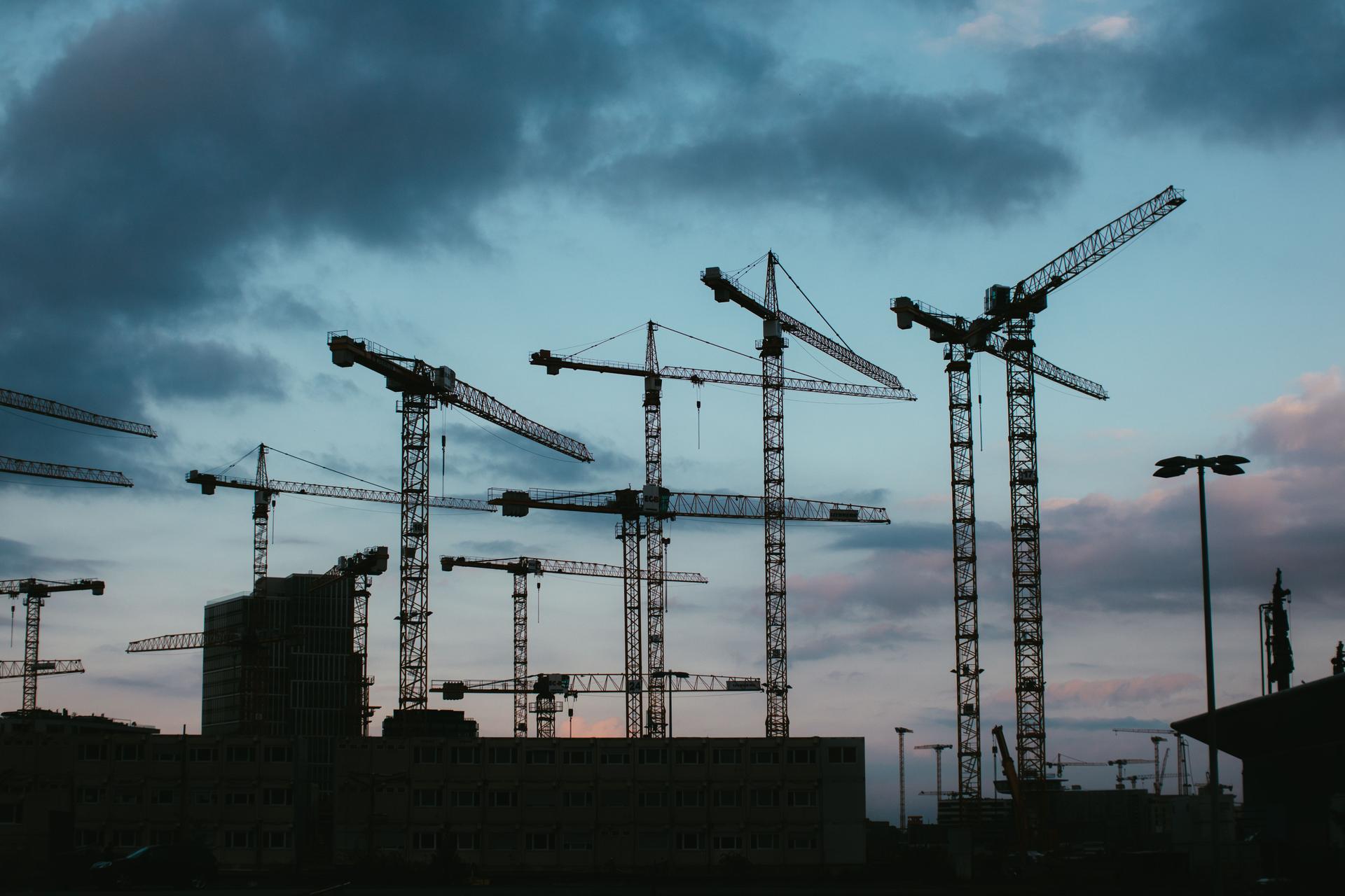 Construction cranes symbolize the challenges of building AI datacenters amid innovation hurdles.