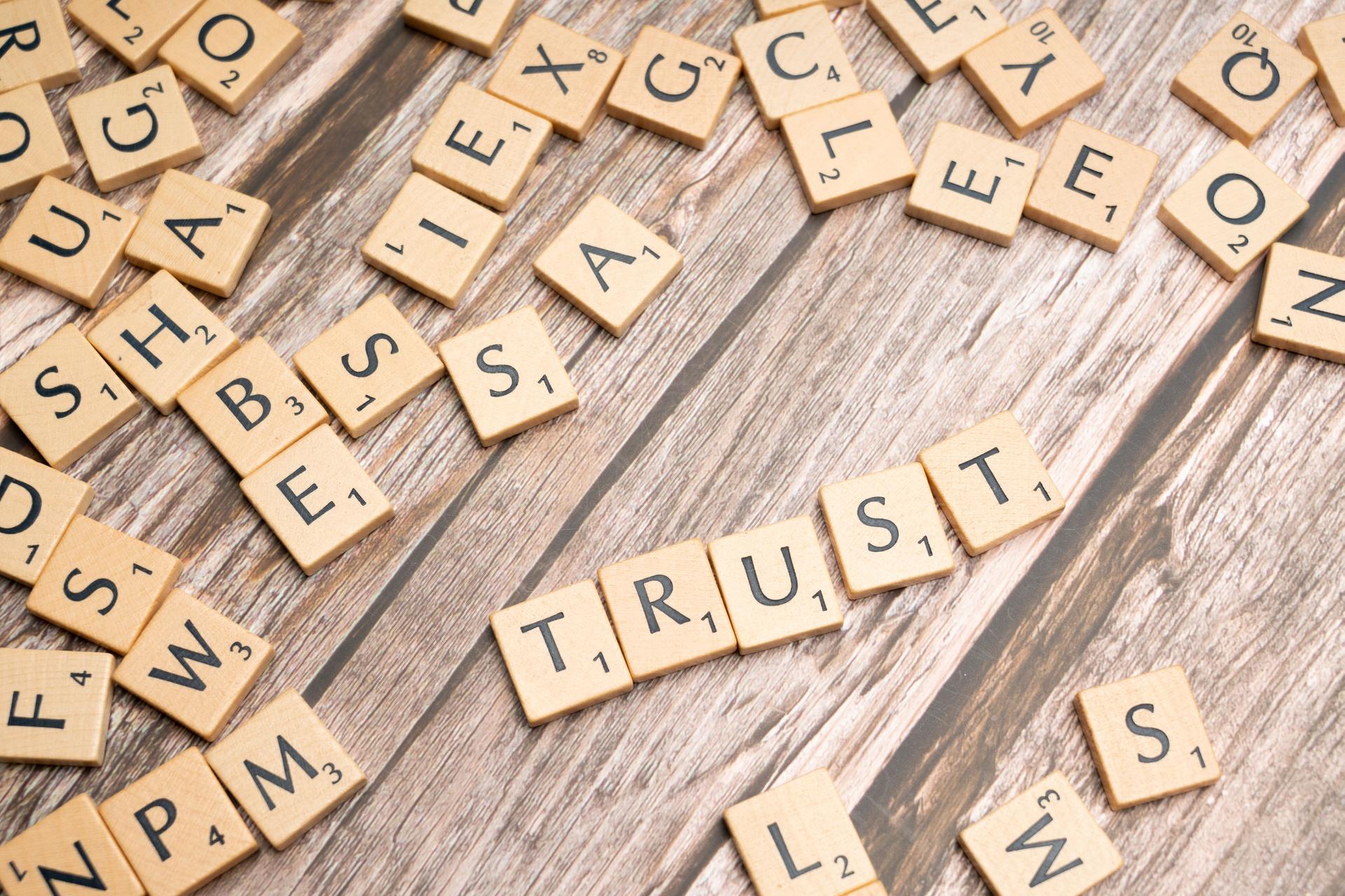 Wooden tiles spelling TRUST represent consumer confidence in AI-disclosed advertising.