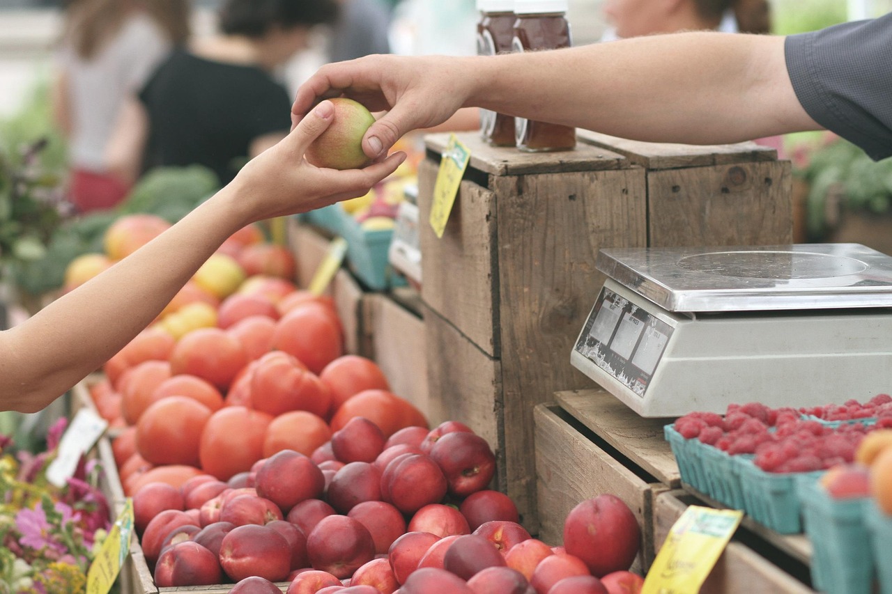Customer buying an apple at a farmers market, illustrating repeat purchase decisions and consumer trust after AI advertising.
