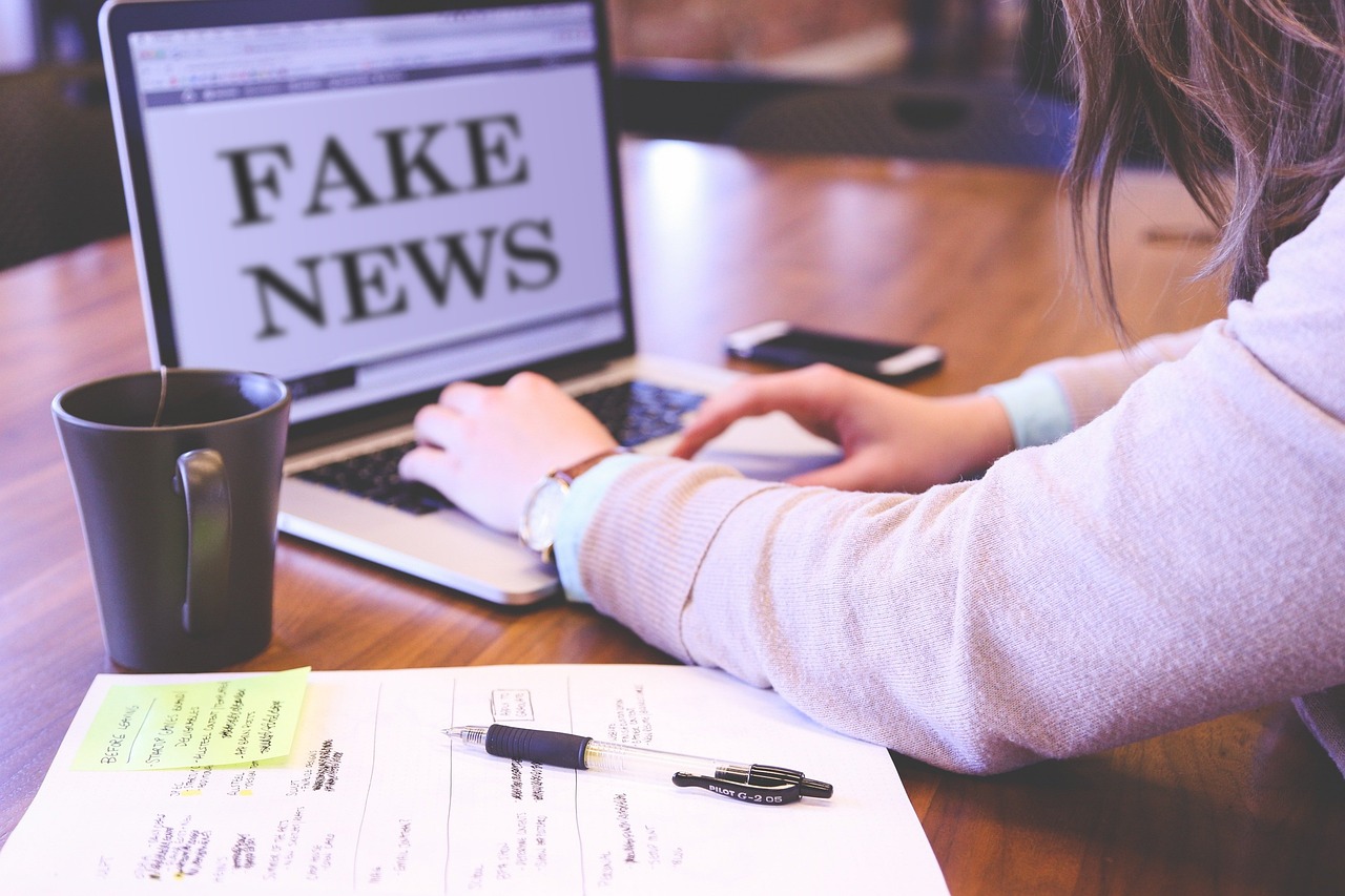 Person typing on a laptop as fake news fuels AI propaganda and attacks on public trust