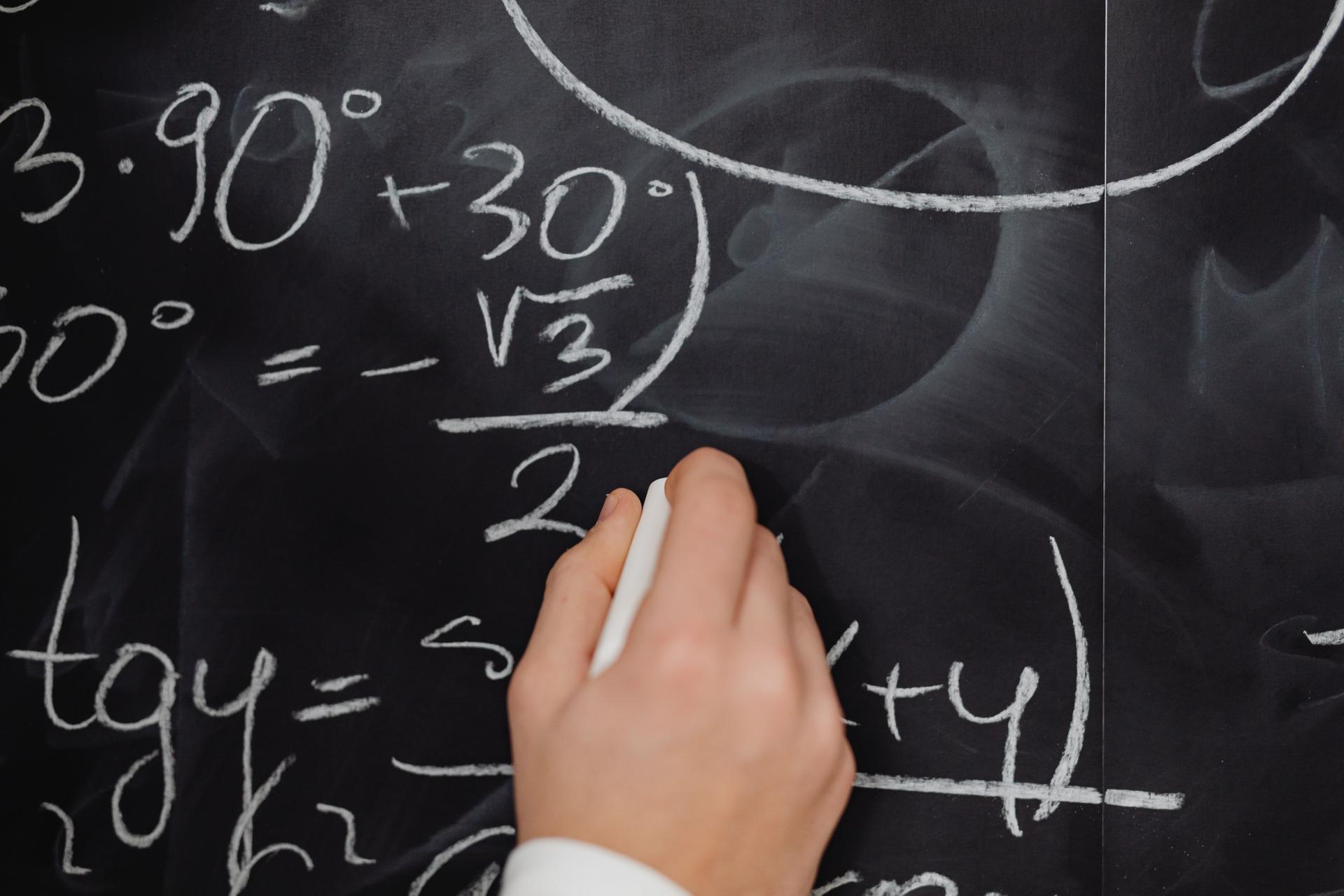 Hand writing mathematical formulas, showcasing AI's role in solving complex problems in ai news
