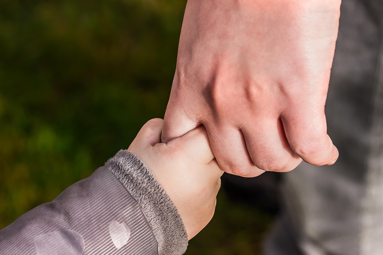 Adult and child holding hands symbolize public trust in shared AGI safety standards.