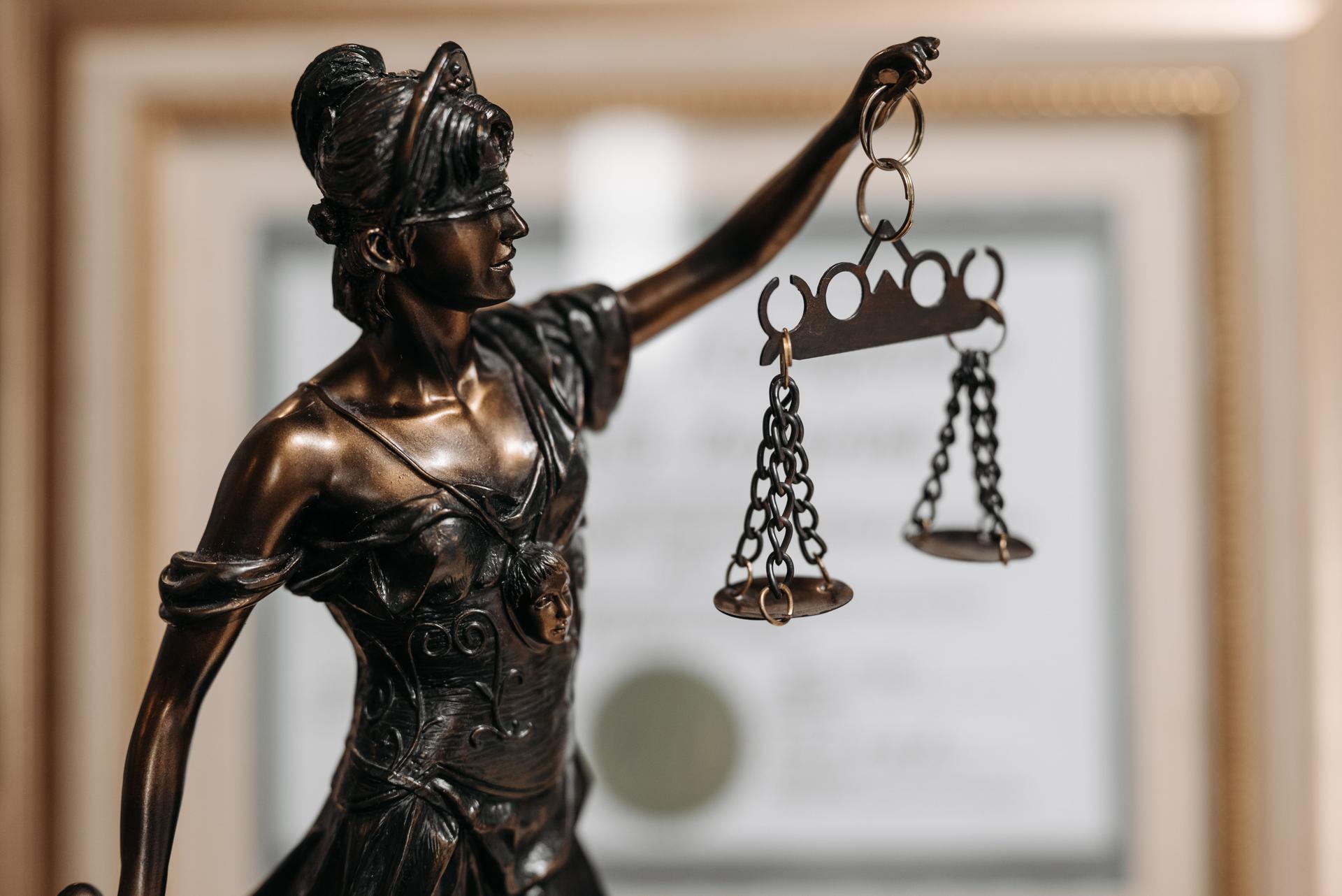 Justice Figure in Law Office Amid AI Ethical Concerns Bronze statue of blindfolded woman symbolizing justice amid concerns over AI ethics in law firms