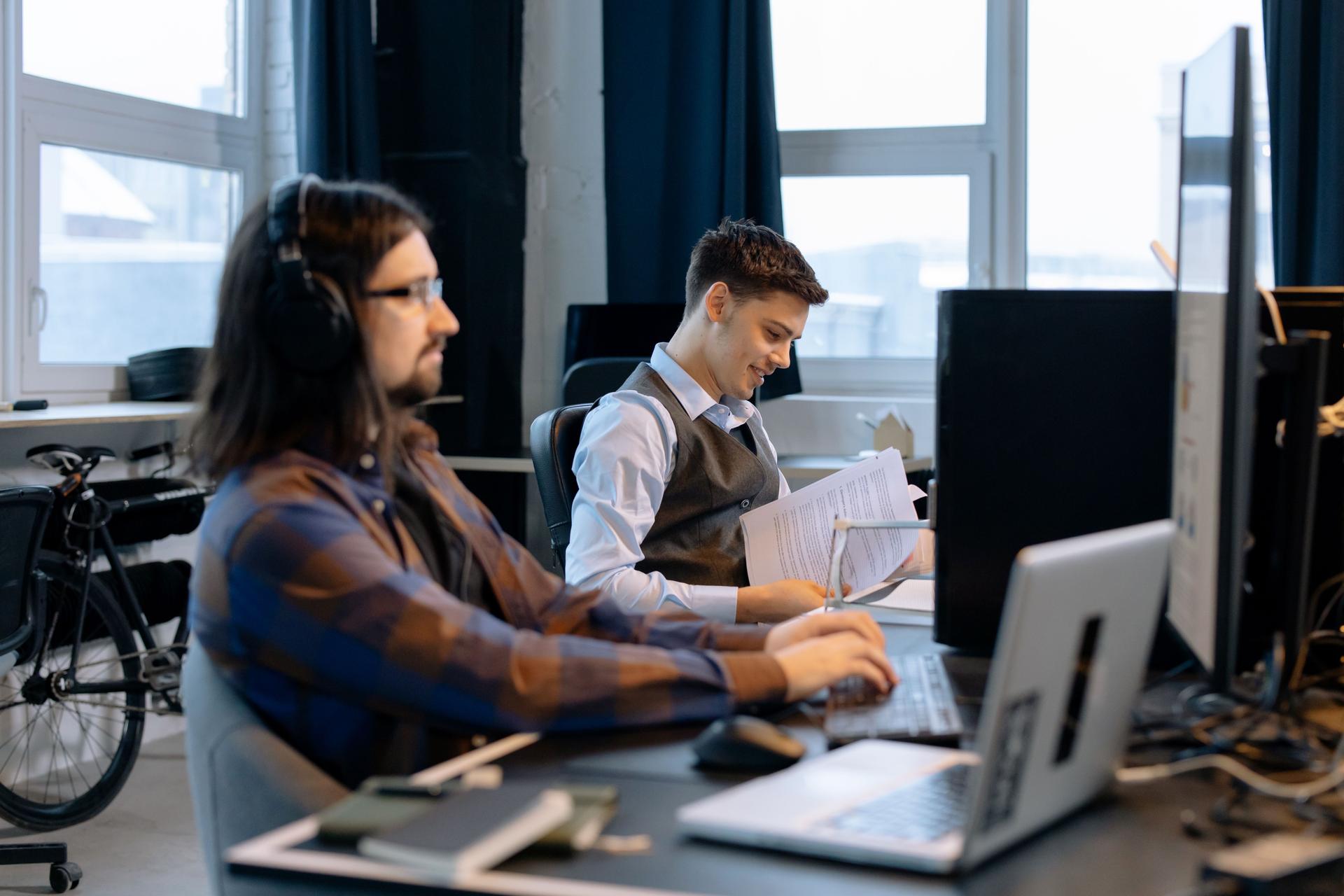 Two young men collaborating in an office as AI technology influences cybersecurity practices.