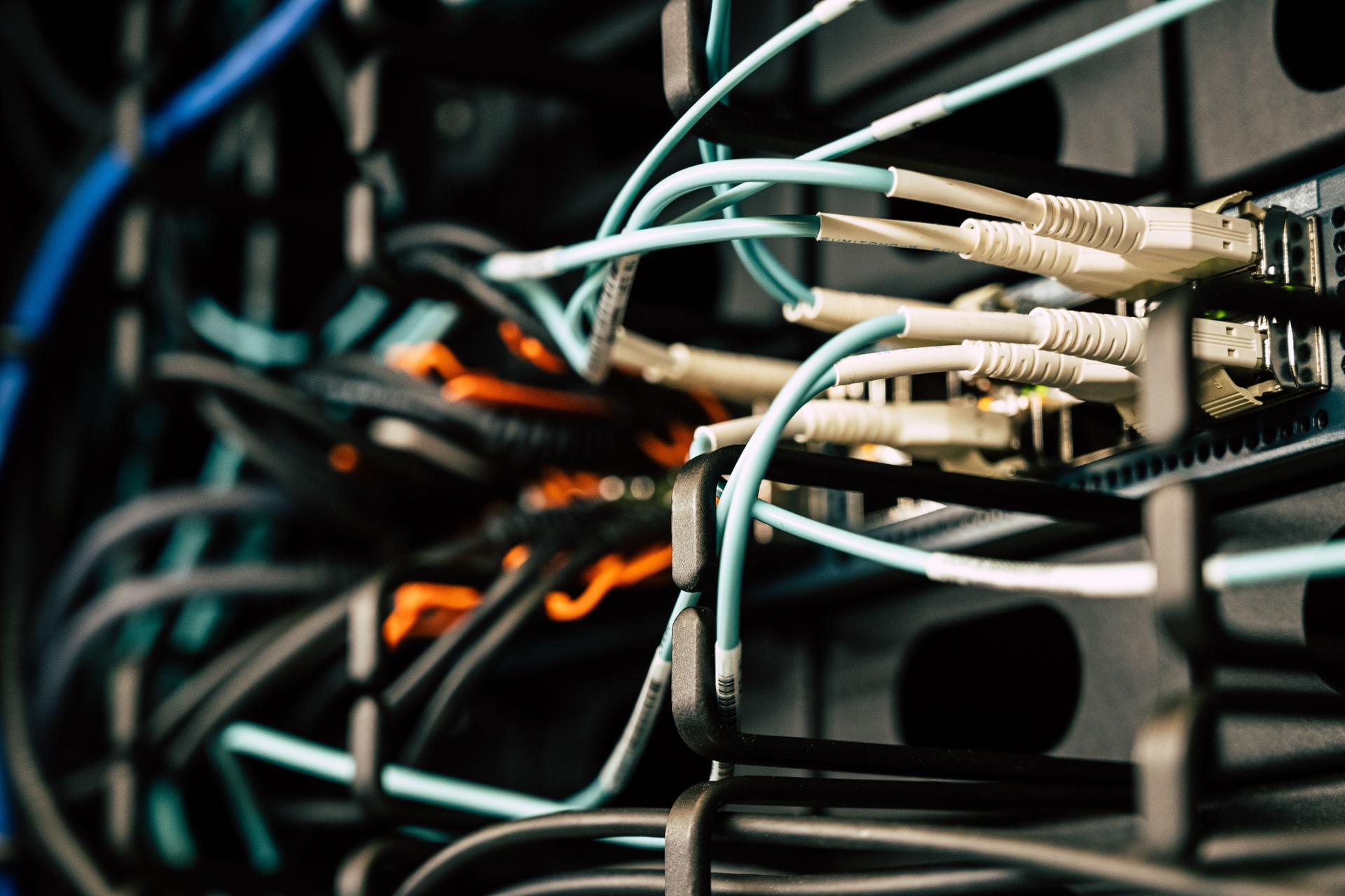 Close-up of electronic cables connected to a network, illustrating the infrastructure behind AI propaganda networks.