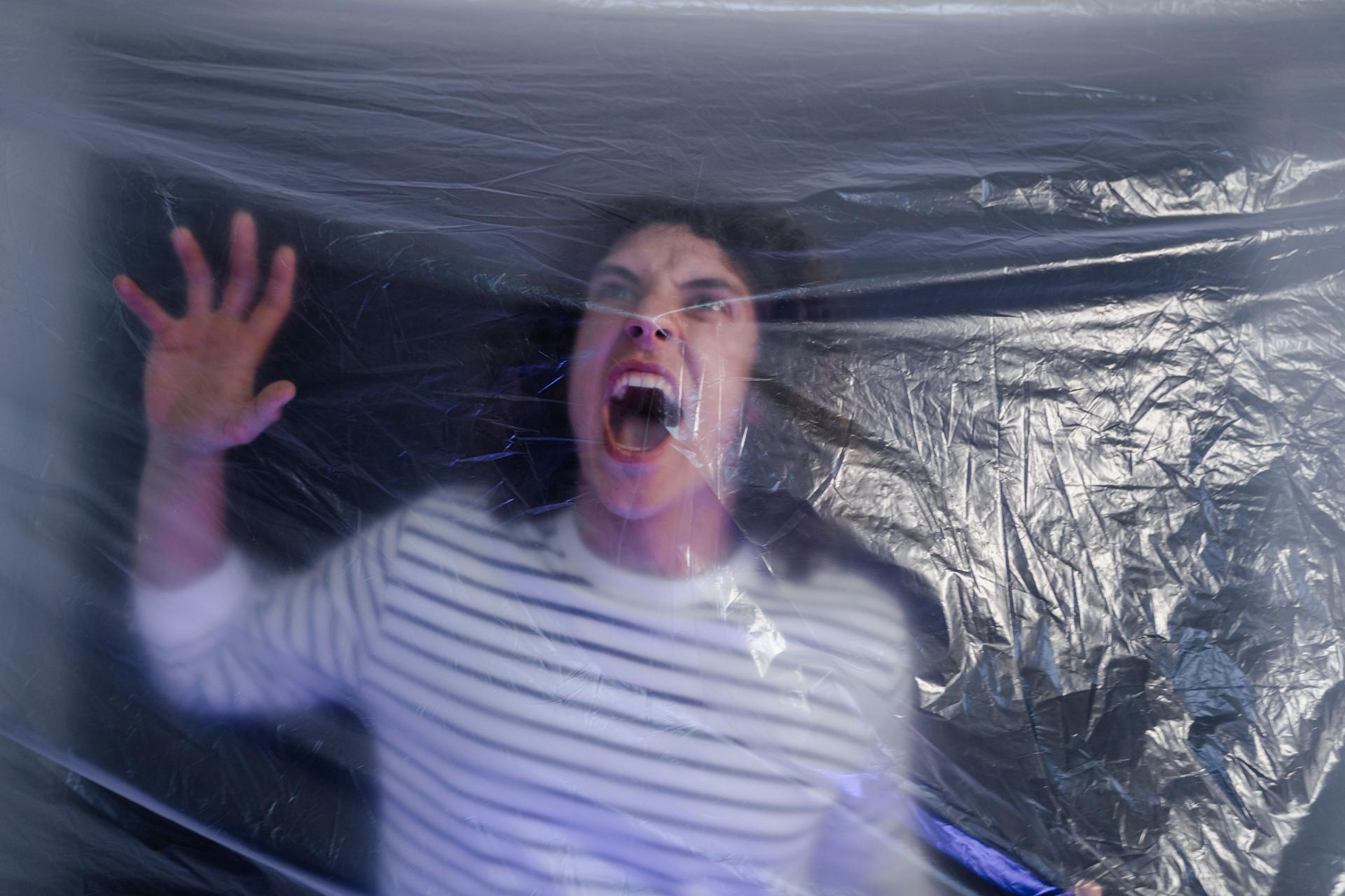 A person appears frightened while restricting an AI agent behind a foil barrier, symbolizing security layers.