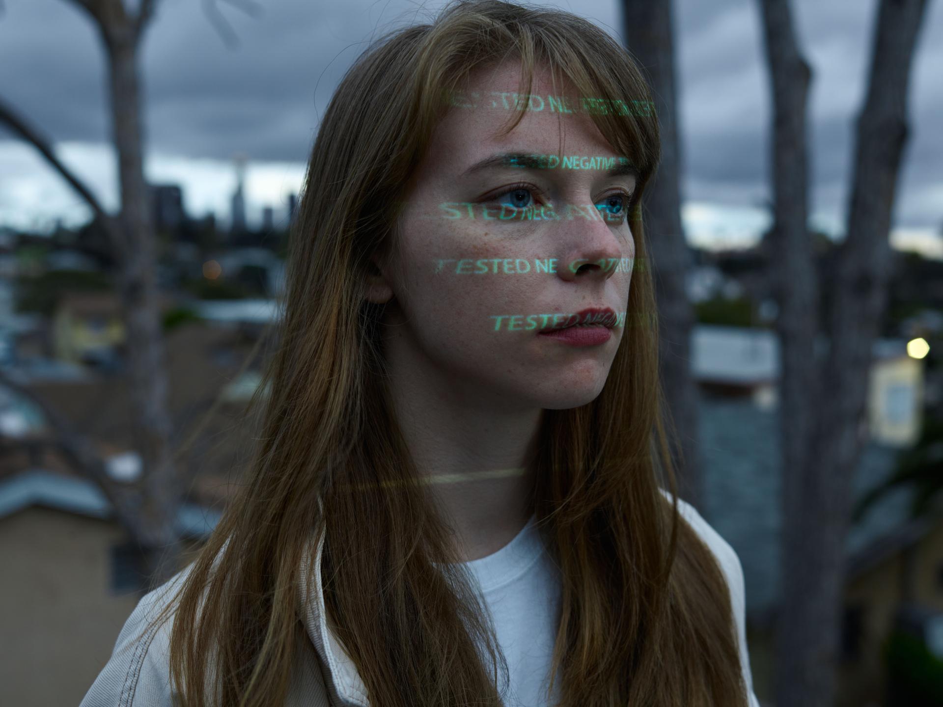 A woman on a rooftop contemplates the challenges of AI cross-testing for safety evaluations.