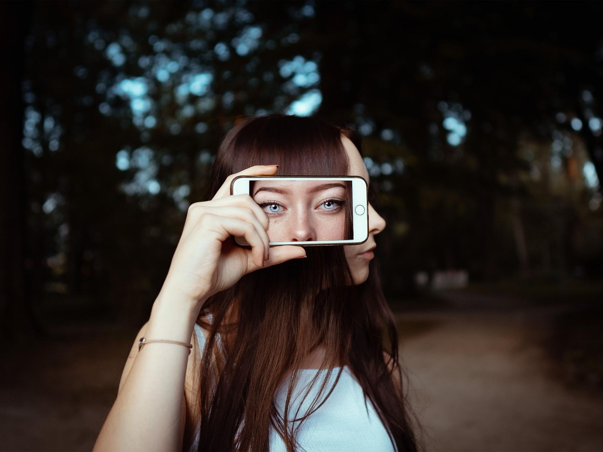 Young Woman Verifying Image Integrity with iPhone 18 Pro Young woman using iPhone 18 Pro to verify image authenticity amid deepfake concerns.